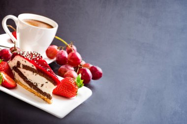 Arka plan. Tatlı ve kahve. Krema, kek ve meyve ile sıcak kahve bir fincan. Üzüm, çilek ve meyveli kek. Karanlık bir arka planda natürmort. Kahvaltı.