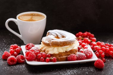 Bir fincan kahve, kek ve kırmızı böğürtlen ve fonda kuşüzümü.