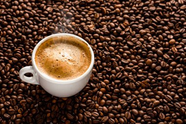 Kahve çekirdeğinin arka planında kahve fincanı.