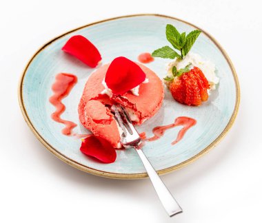 Mavi tabakta kremalı ve çilekli pembe tatlı.