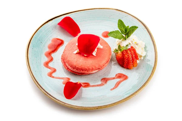Mavi tabakta kremalı ve çilekli pembe tatlı.
