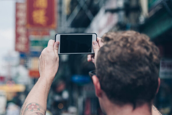 Man  holding a smart phone in the street of chinatown in bangkok