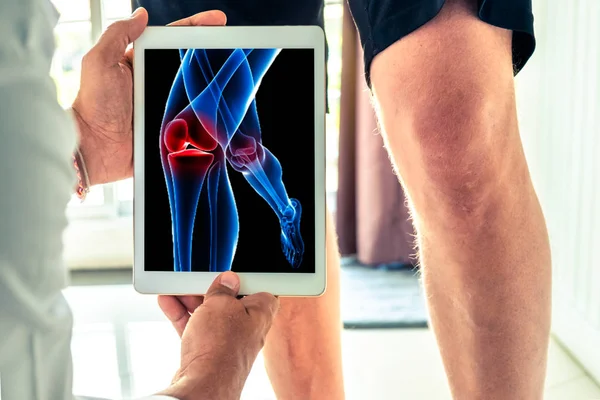 Doktor hastaya bir dijital tablet teknoloji 3d x-ışını diz ağrısı olan ile tutarak