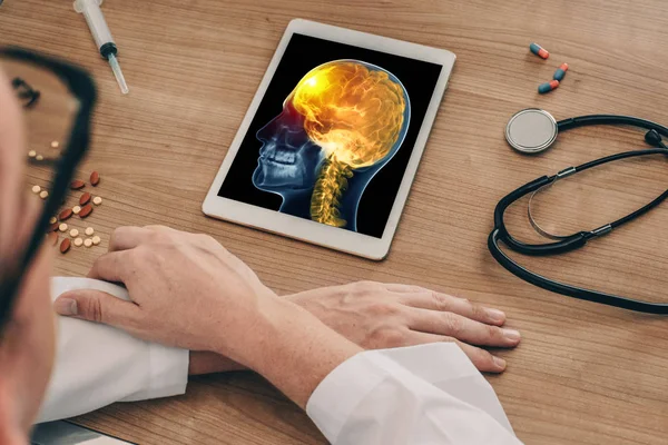 Doktor beyin ve boyun önünde ağrı ile kafatası kafa x-ray ile bir dijital tablet izliyor. Migren baş ağrısı kavramı