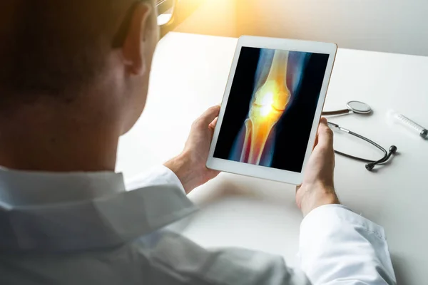 Arts met een digitale tablet met Röntgenstraal van pijn op een knie. Vooraanzicht — Stockfoto