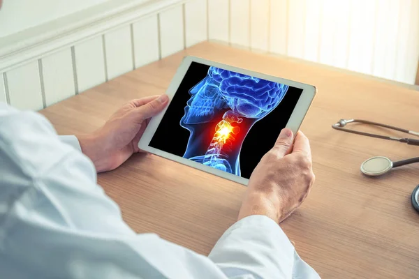 Doktor boynunda ağrı ile 3d kafatası x-ray ile bir dijital tablet tutan. Baş ağrısı migren veya travma kavramı