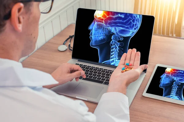 Doktor bir dizüstü bilgisayarda beynin önünde ağrı ile 3d kafatası kafası x-ray ile hap tutan. Masanın üzerinde dijital tablet