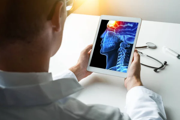 Doktor beynin önünde ağrı ile 3d kafa x-ray ile bir dijital tablet tutan. Migren baş ağrısı kavramı