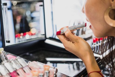 Asyalı kadın bir ayna ile kırmızı dudaklar kullanarak