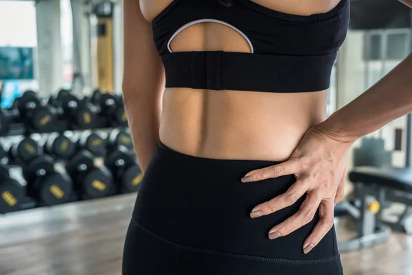 Mujer sosteniendo sus caderas en el gimnasio. Concepto de lesión lumbar — Foto de Stock