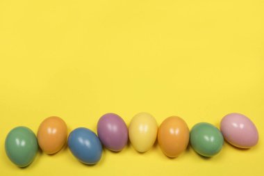 Paskalya yumurtaları kopya alanı ile sarı bir arka plan üzerinde pastel renkli