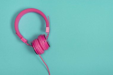 Kopyalama yeri olan mavi bir arka plan üzerinde pembe kulaklık