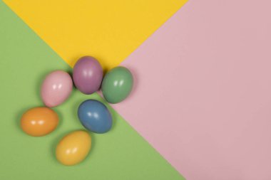 Bir pastel renkli yeşil, sarı ve pembe renkleri ve kopya alanı ile arka plan üzerinde renkli Paskalya yortusu yumurta
