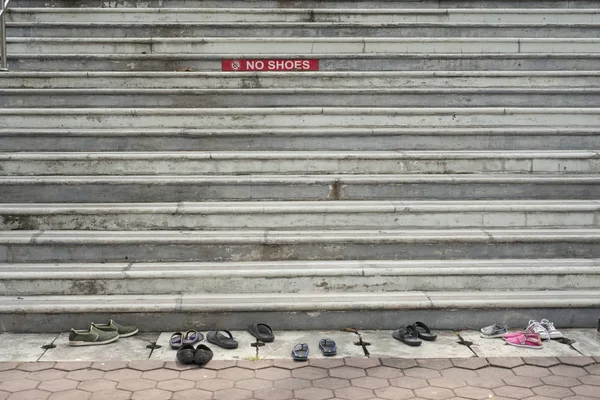 Steps of a stone stair to a temple with a red sign no shoes and shoes in front of the stairs
