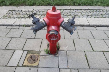 Kırmızı eski moda yangın pompası ve Anvers bir yürüyüş sokakta Demir gaz rögar kapağı