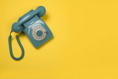 Mavi retro telefon sarı bir arka plan üzerinde yüksek bir açıdan görüldü