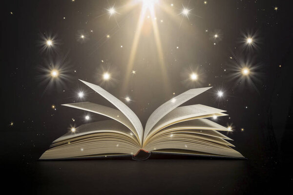 Открытая книга со звездами и ярким светом на черном фоне
