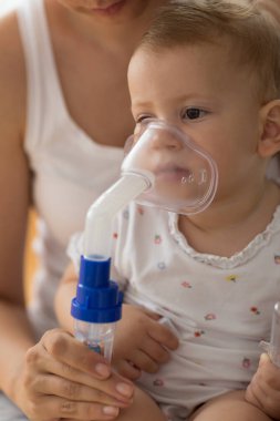 Bebek alarak solunum enhalasyon tedavisi. Bir nebülizör maskesi tutan anne