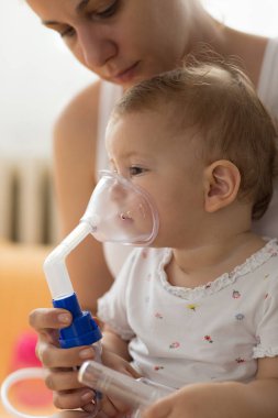 Bebek alarak solunum enhalasyon tedavisi. Bir nebülizör maskesi tutan anne