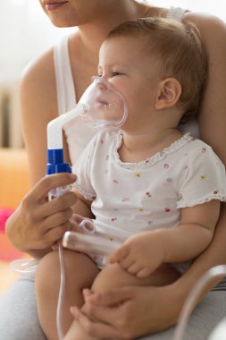 Bebek alarak solunum enhalasyon tedavisi. Bir nebülizör maskesi tutan anne