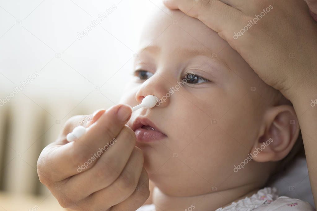 mother cleaning babies nose with cotton swabs