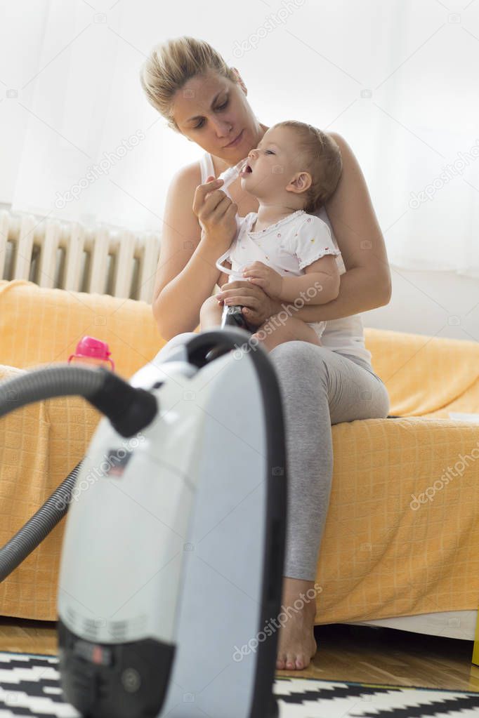 mother cleaning babies nose. nasal aspiration connected to vaccum cleaner
