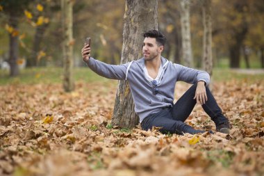 Yakışıklı adam doğada bir kitap okuma. Sonbahar yaprakları. Kopya alanı