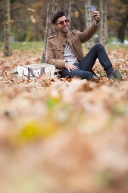Genç yetişkin adam yakışıklı alarak selfie ahşap, kış sonbahar günü içinde
