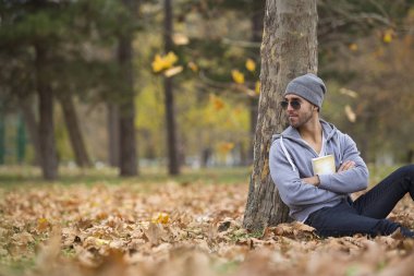 Yakışıklı adam doğada bir kitap okuma. Sonbahar yaprakları. Kopya alanı