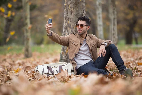 Young adult man handsome taking selfie in the wood, winter autumn day