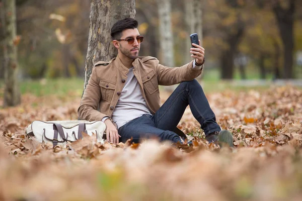 Young adult man handsome taking selfie in the wood, winter autumn day