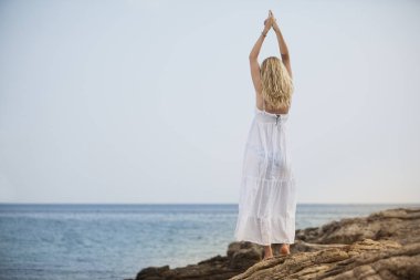 Yoga yapan ve kumsalda dinlenen bir kadın.