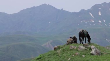 Erkekler dağın tepesinde oturmuş tarlaları gözlüyorlardı.