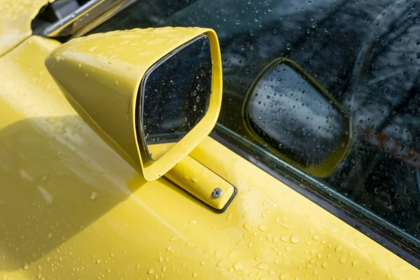 Rearview mirror on a yellow old muscle car.
