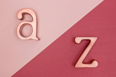 Metal altın A ve Z harfleri pembe ve kiraz kırmızı zemin üzerine yükseldi..