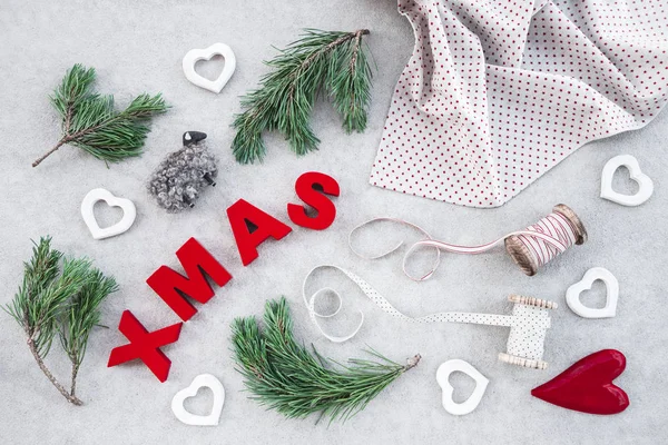 自然の要素を持つクリスマスの装飾 小さな羊 松の木の枝 綿の布 リボン およびコンクリート背景上の単語クリスマス — ストック写真
