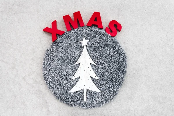 Christmas decoration in Nordic style. Sheep skin, metal fir tree and the word Xmas on light gray background.