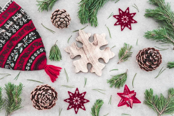北欧风格的圣诞装饰 红色针织冬帽 绿色松树树枝 锥和星星 在混凝土背景 — 图库照片