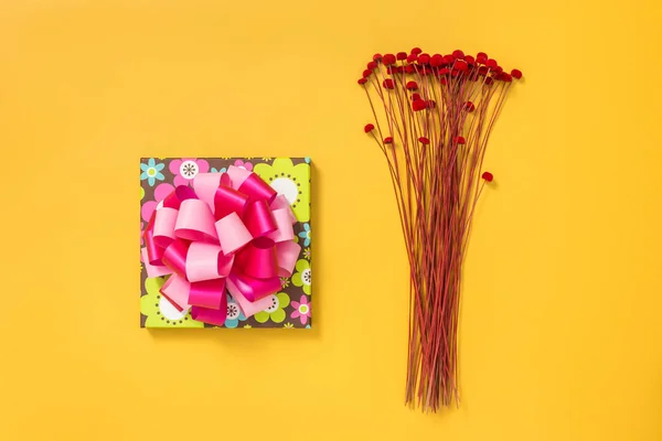 明るいギフト用の箱 黄色の背景に赤のドライフラワーの花束 — ストック写真