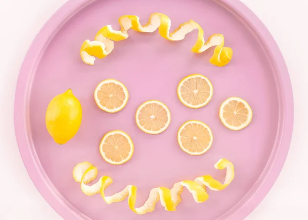 新鮮なレモンとスパイラル ピンクのラウンド トレイに皮をむきます 剥離や柑橘類の果物を切って — ストック写真