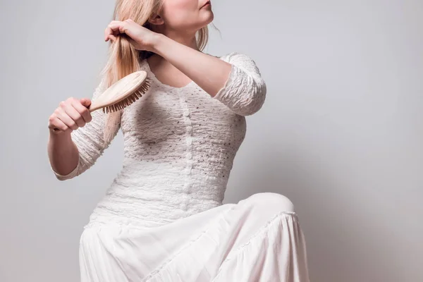 Signora in bianco spazzolando i capelli biondi — Foto Stock
