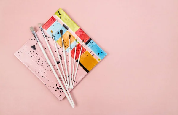Renkli seramik tabak ve pembe bir arka plan üzerinde Boya fırçaları — Stok fotoğraf