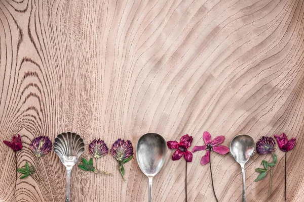 Flores silvestres y cucharas de plata en la superficie de madera —  Fotos de Stock