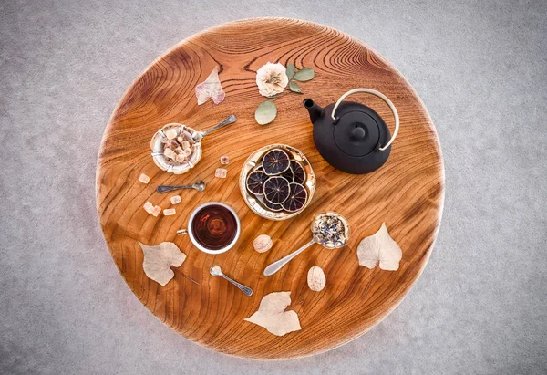 Tea, flowers and sweets on round wooden table