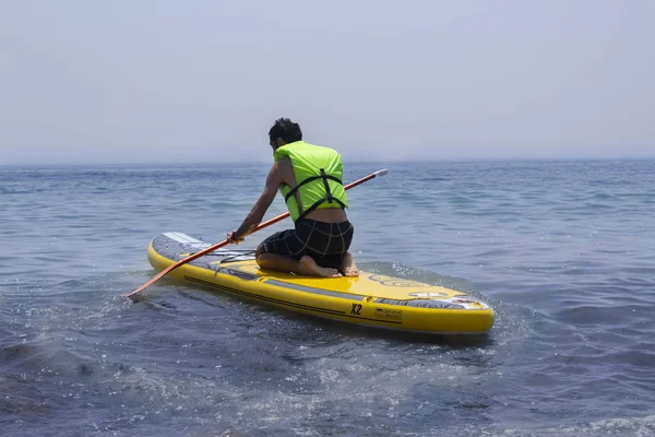 Man practicing paddle surf kneeling on the board