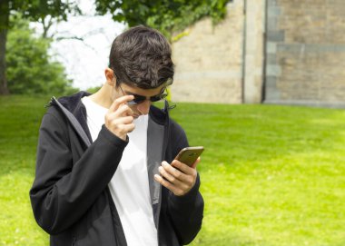 Çocuk parkta telefonuna bakıyor.