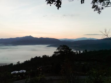 Bulutlar ve sis kaplı dağın başında.