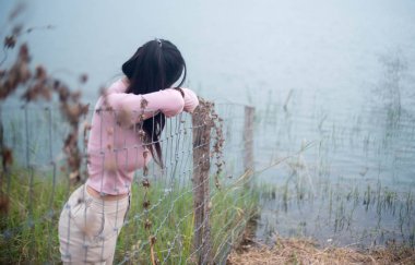 Genç bir kadın çaresizlik içinde çit eğildi.