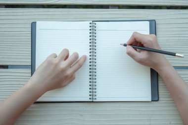 Kadın sarı bir arka plan ile bir kil kitap kitap yazdı. Üstten görünüm.