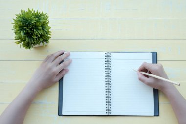 Kadın sarı bir arka plan ile bir kil kitap kitap yazdı. Üstten görünüm.